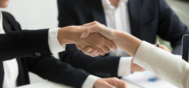 two people shaking hands in front of a laptop by Radission US courtesy of Unsplash.